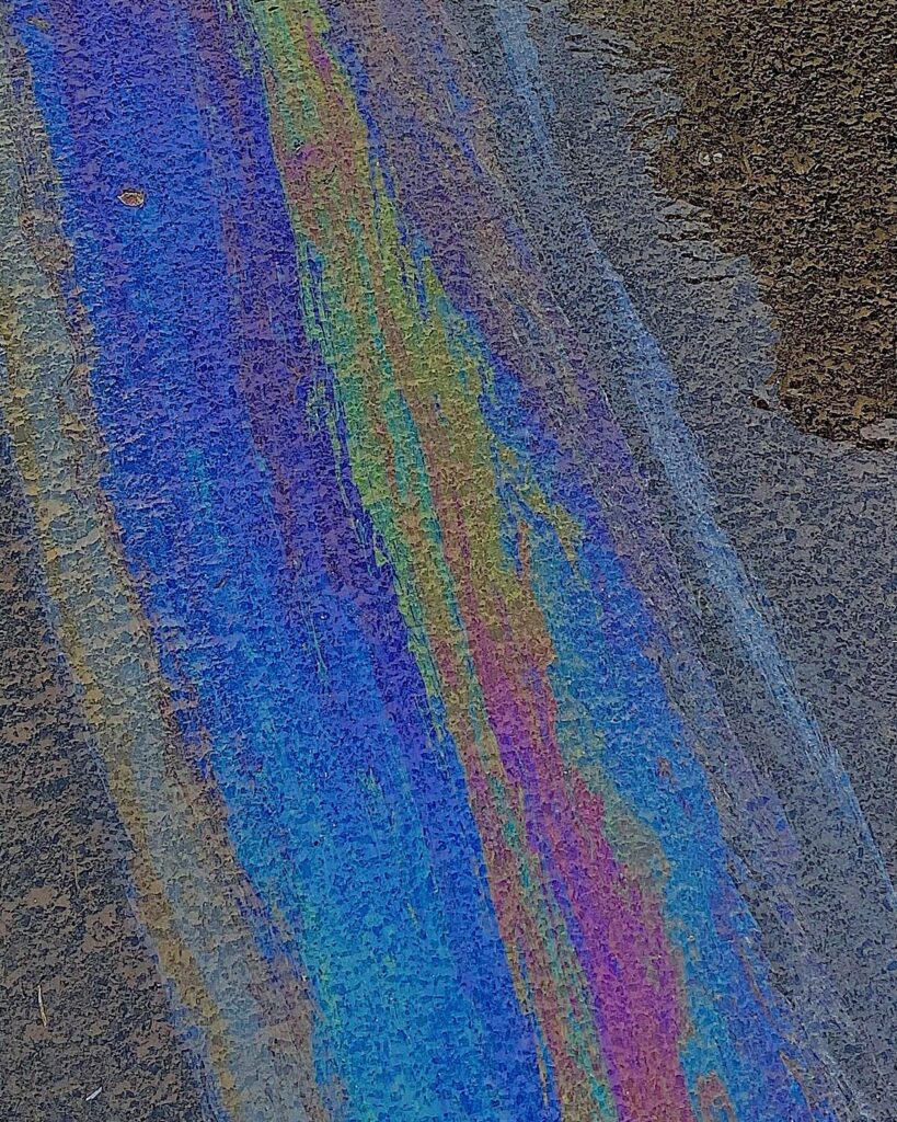 Colorful oil slick creating a vibrant abstract pattern on asphalt.